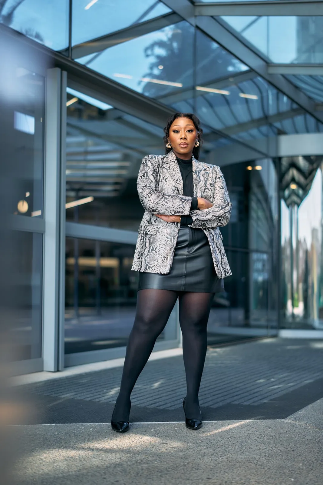 Lebo Lion in a snakeskin blazer standing outside a glass-roofed office building